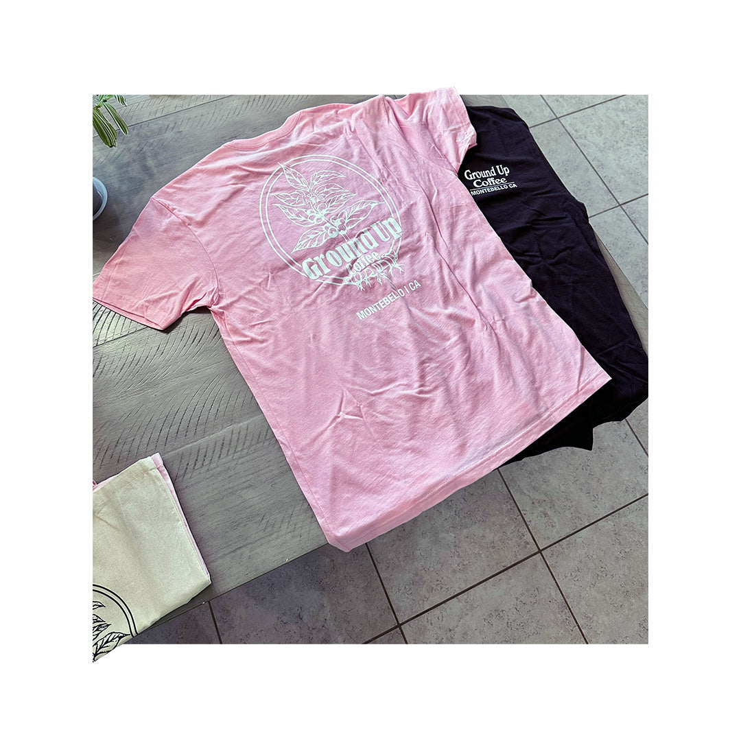Next Level 3600 light pink cotton T-shirt with Ground Up Coffee logo printed on back, shown stacked on black shirt with same design.