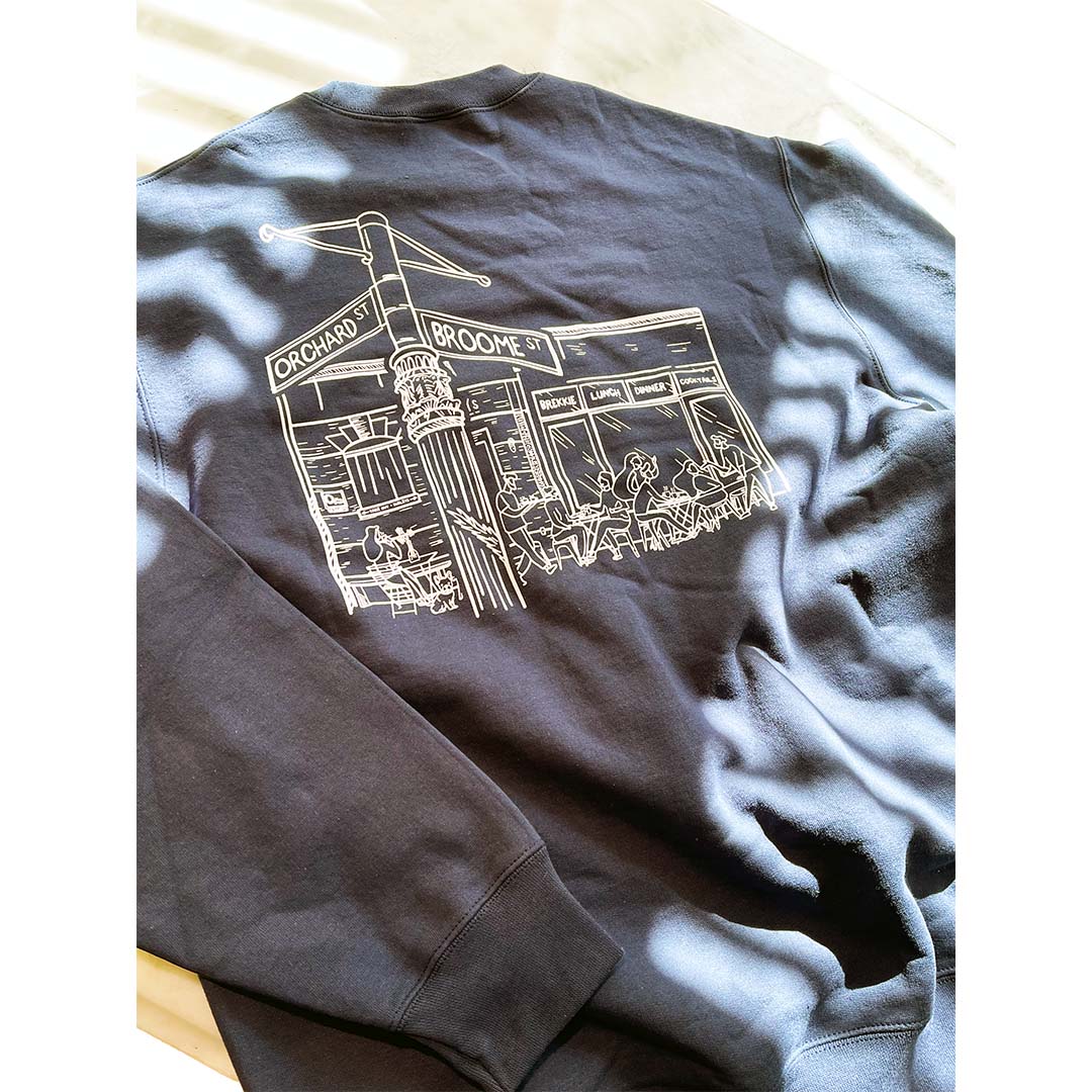 Gildan crewneck sweatshirt with large back print of a hand-drawn city street corner featuring Orchard and Broome signs