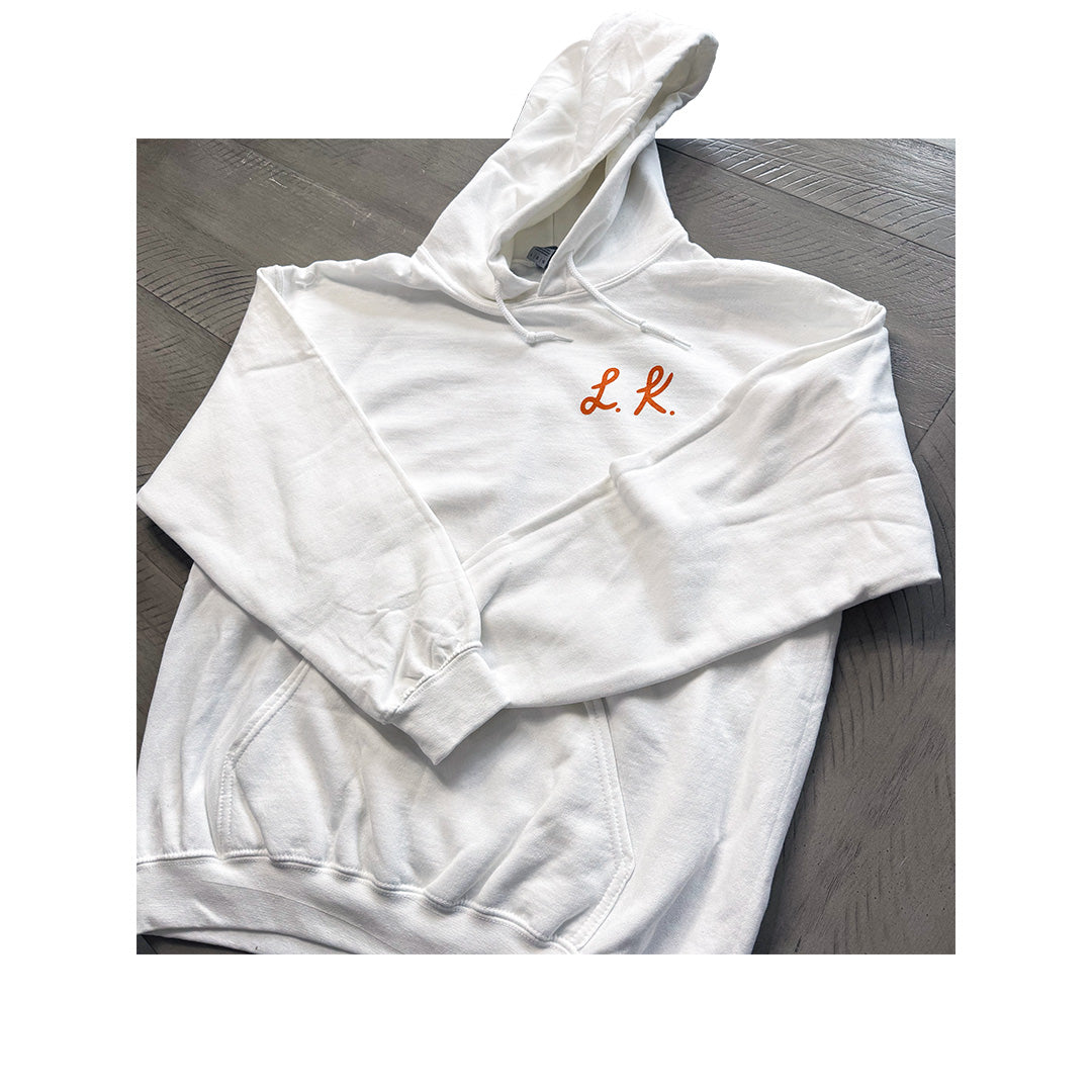 Independent Trading Co. heavyweight white hoodie with custom L.K. initials embroidered in orange on chest.
