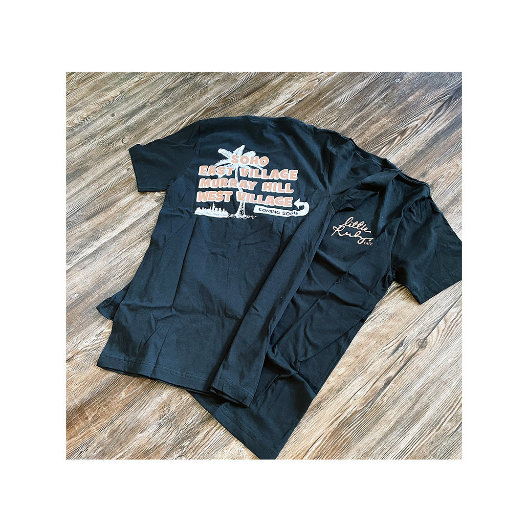 Two black Rubys t-shirts displayed flat—one showing a front embroidery logo, the other showing a city graphic with locations and “coming soon” text