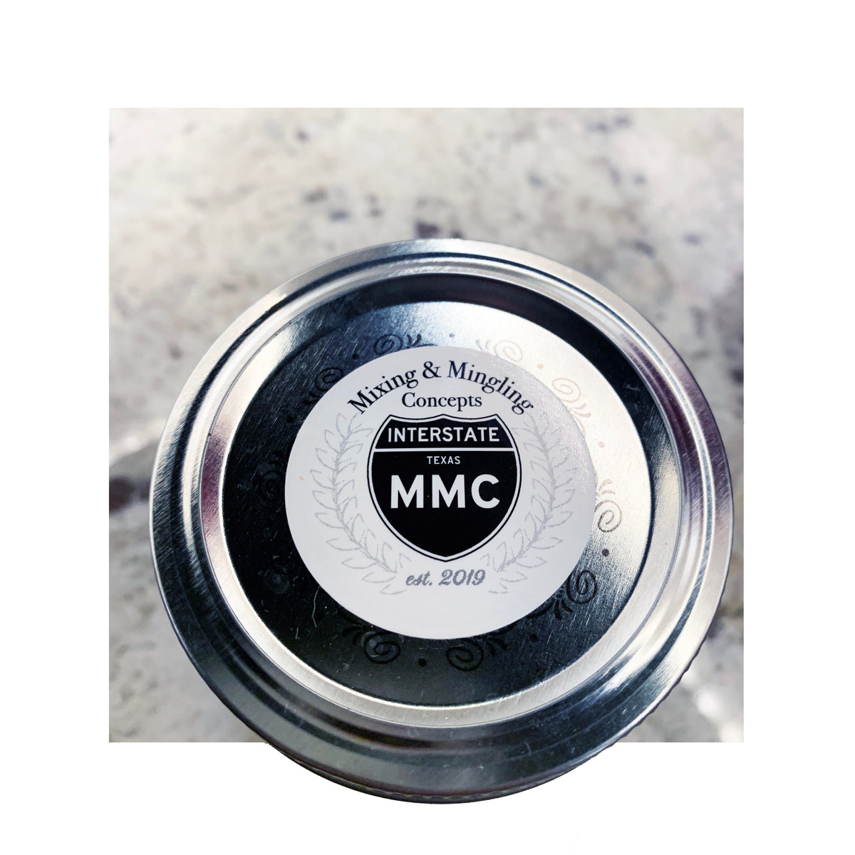 Custom circle label for Mixing & Mingling Concepts applied to silver metal jar lid, black and white design with Interstate Texas MMC logo