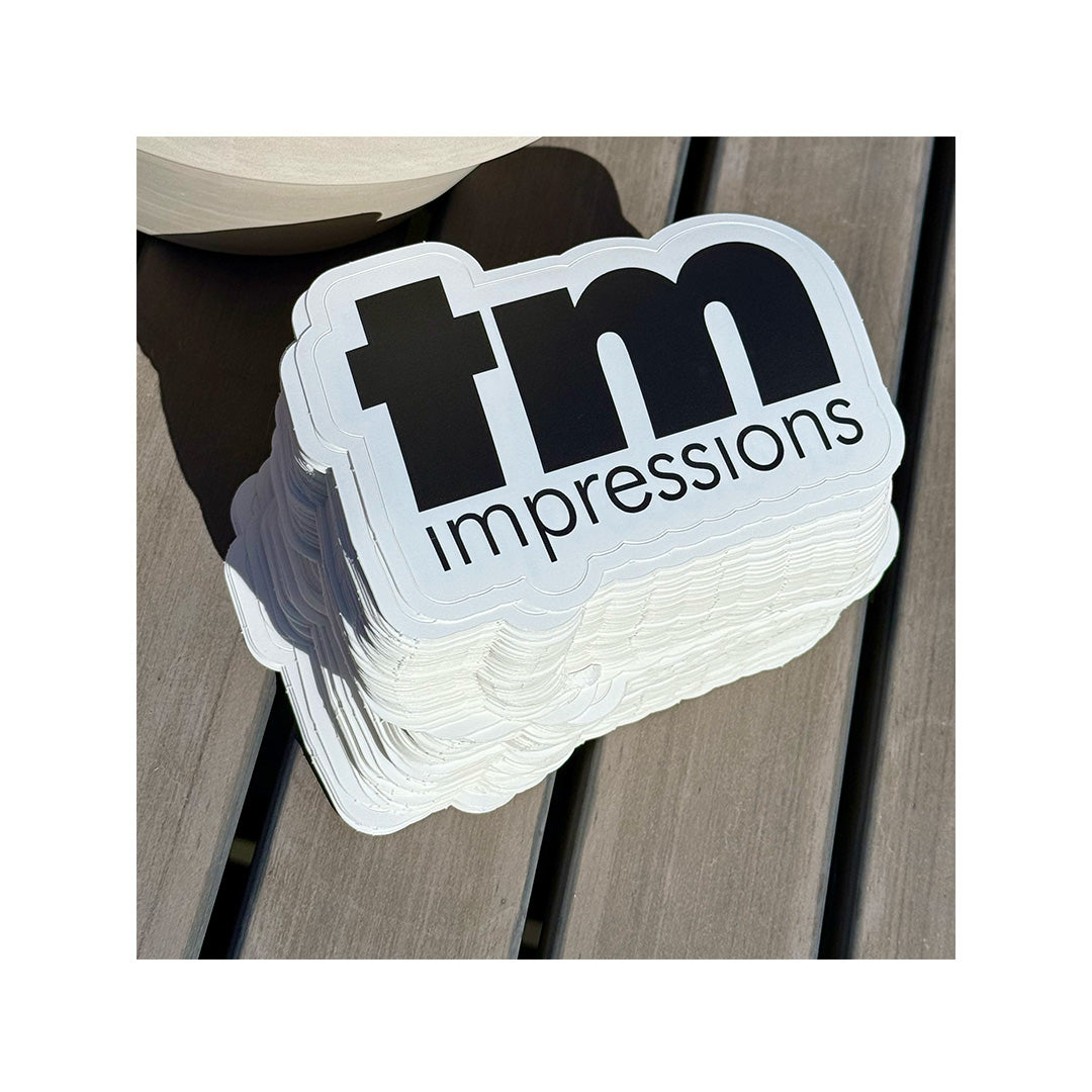 Custom die-cut stickers for Session Taco featuring a wave and sun logo in teal and orange colors, placed on a wooden surface