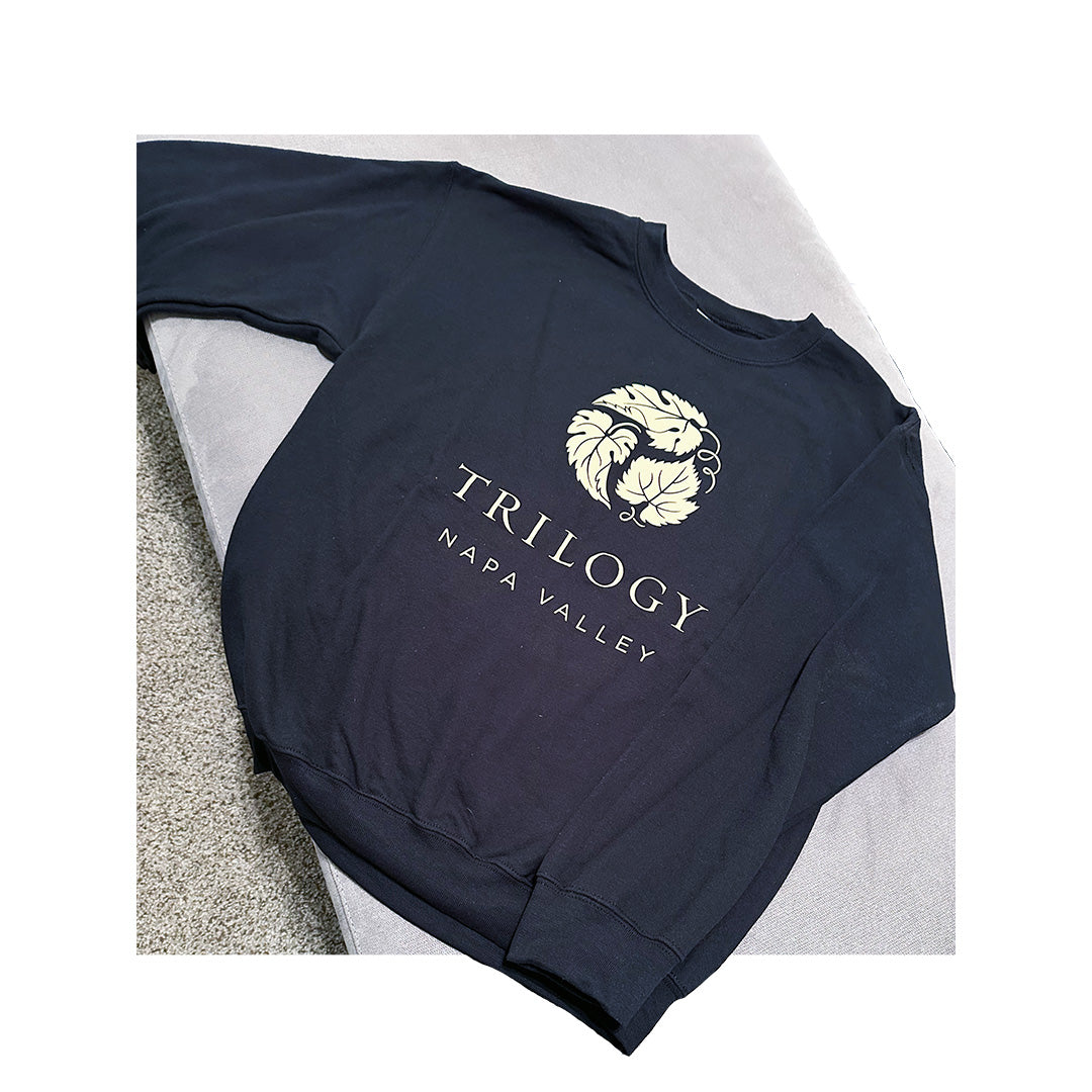 Black Gildan crewneck sweatshirt featuring gold print of the Trilogy Napa Valley logo with vine illustration