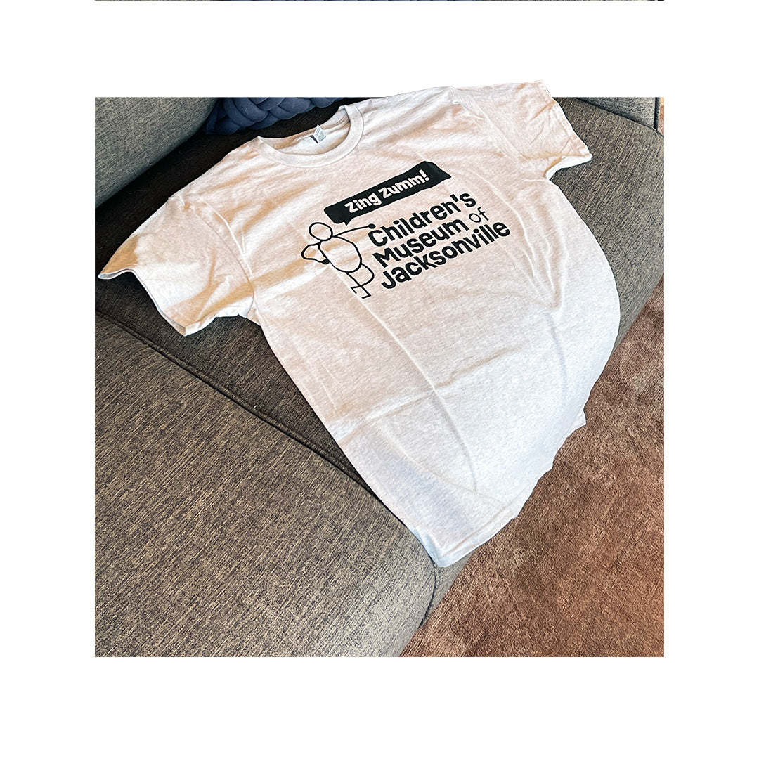 White Gildan 2000 T-shirt with custom black print for the Children’s Museum of Jacksonville, displayed on a couch