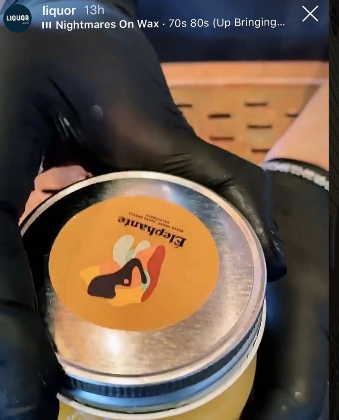 Custom circle label with abstract art design for Elephante restaurant, applied to silver jar lid by gloved hand during packaging