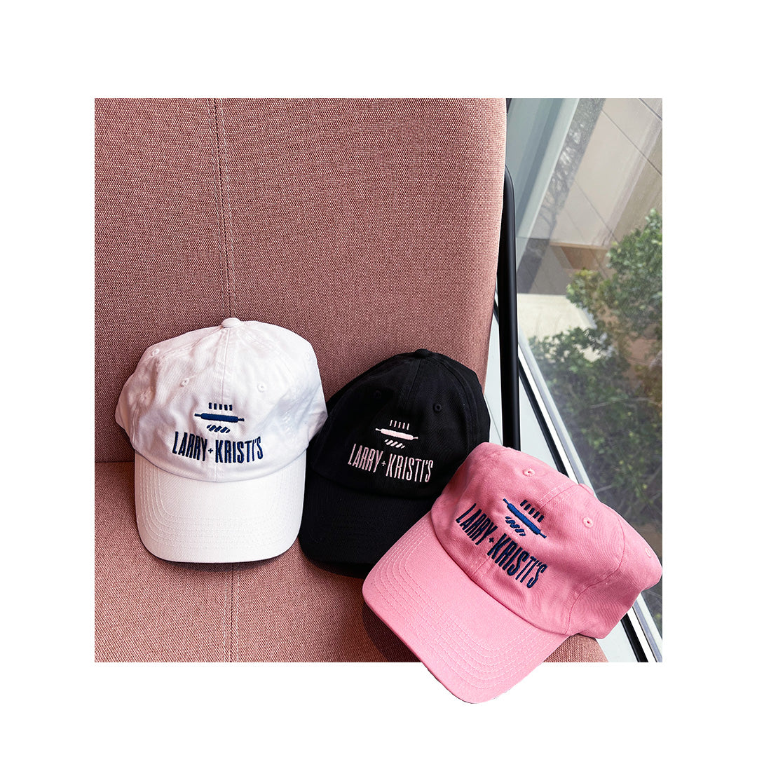 White, black, and pink "Larry + Kristi’s" embroidered dad hats on pink chair – Valucap VC300a