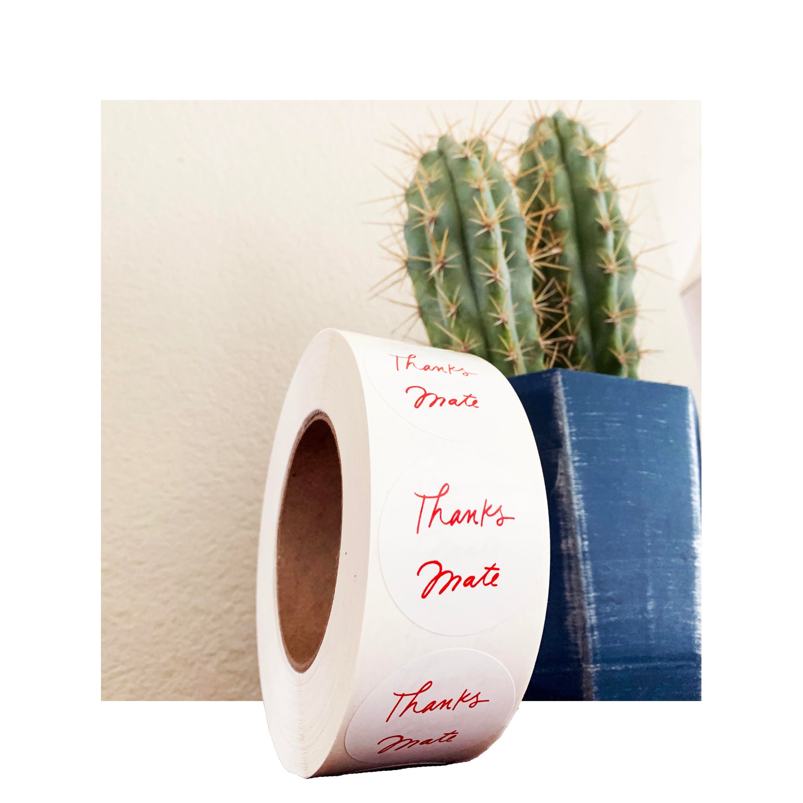 Roll of custom circle labels with red ‘Thanks Mate’ design, matte finish on white BOPP material, displayed in front of cactus